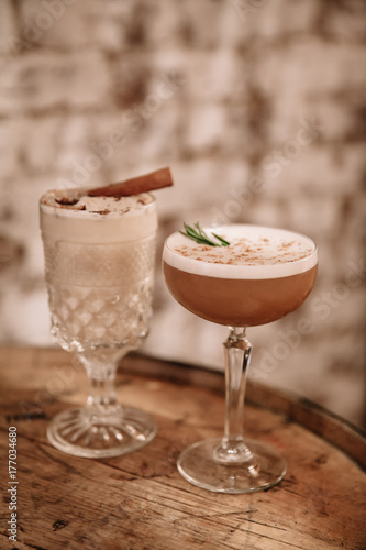 Two creamy alcoholic cocktails against white brick background