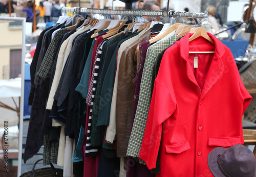 outdoor stand on a flea market with used clothing and a red dres