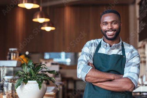 Smiling African entrepreneur standing at the counter of his cafe photo