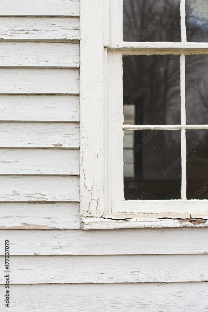 Partial window on the facade of a weathered building painted white Partial window on the facade of a weathered building painted white