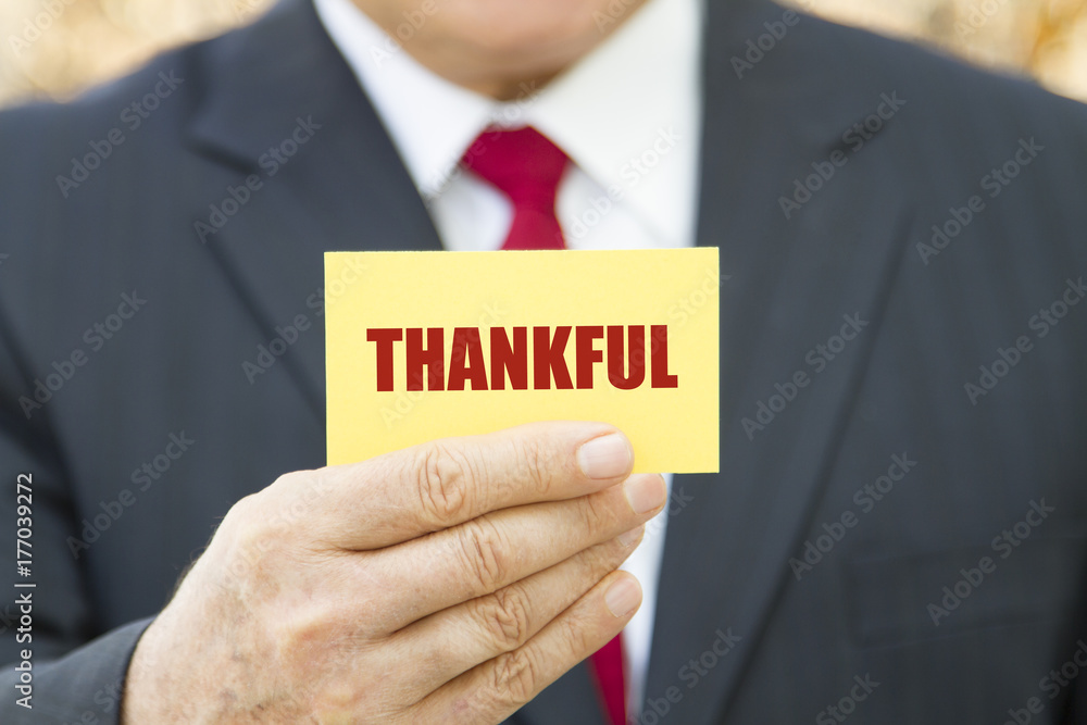 Businessman showing a card with text THANKFUL Businessman showing a card with text THANKFUL