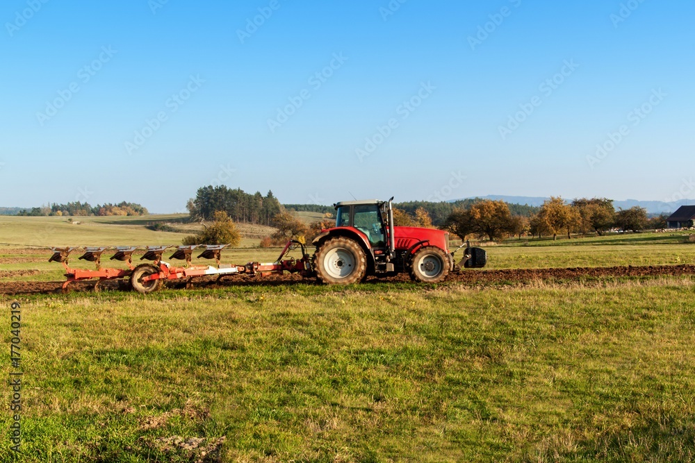 Obraz premium Red tractor pole field. Autumn field work. Life on the farm. Agricultural landscape in the Czech Republic.
