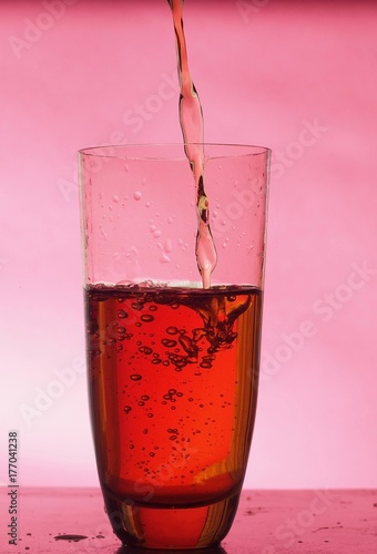 In a clear glass filled with drink. The on Burgundy background.
