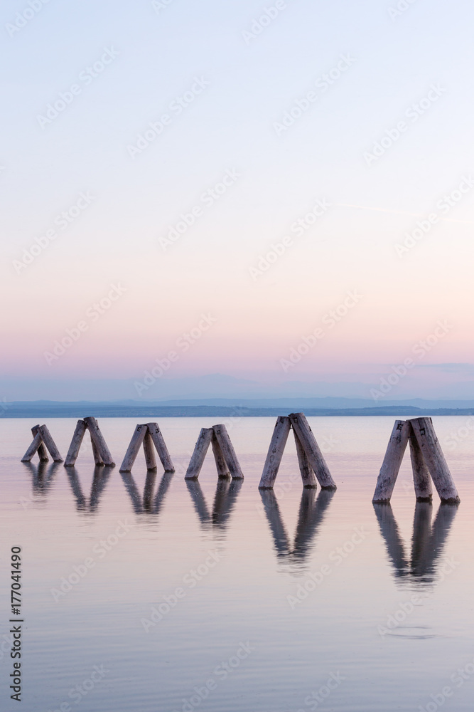 Obraz premium Sunset Impression of wooden pillars at Lake Neusiedl (Podersdorf am See, Burgenland, Austria)