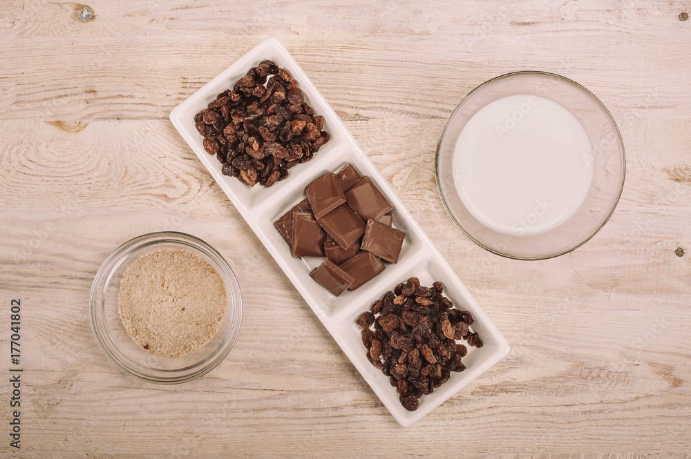 Chocolate bar and dried grapes in white bowl Chocolate bar and dried grapes in white bowl