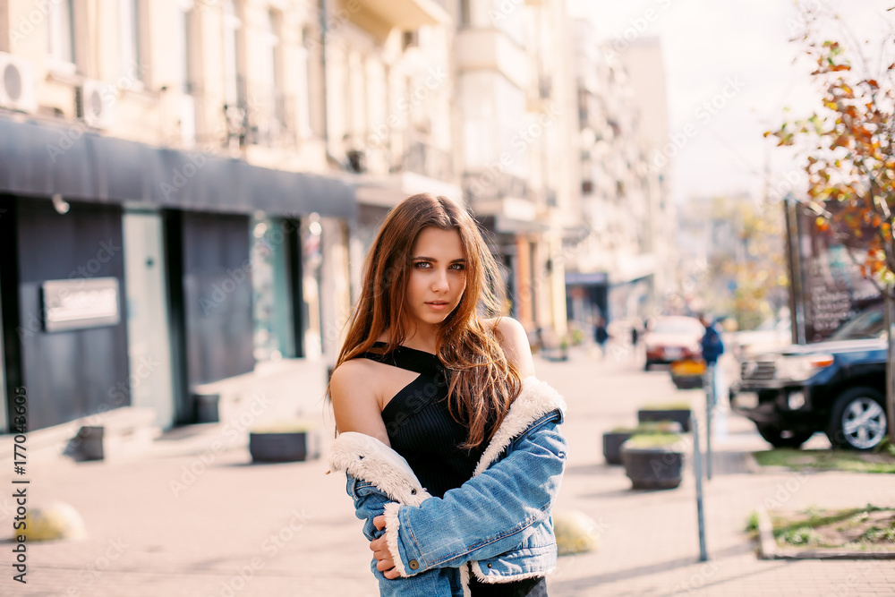 Stylish hipster girl in the retro jeans suit posing in the street