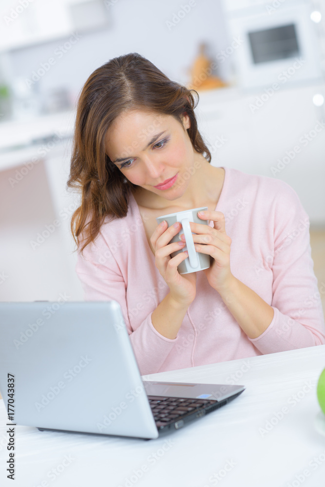Lady holding cup and looking at computer screen Lady holding cup and looking at computer screen