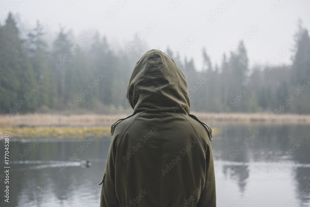 Woman wearing a parka and looking at the lake Woman wearing a parka and looking at the lake