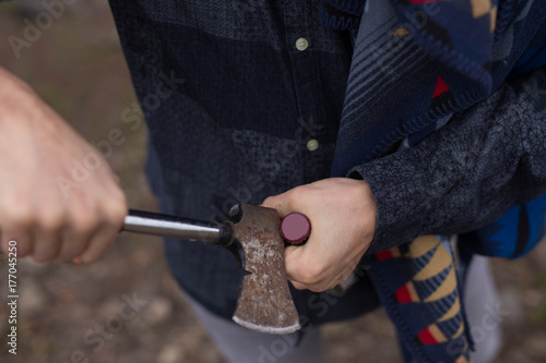 Man opening beer bottle with axe head. photo