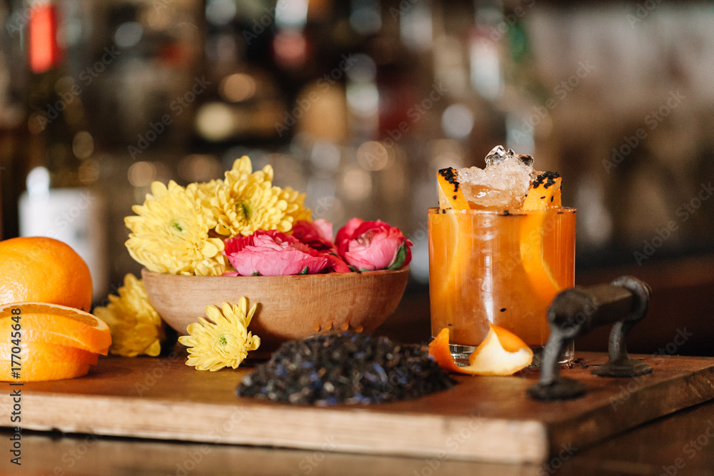 A colorful alcoholic rum cocktail with ingridients such as oranges, tumeric and black sesame seeds