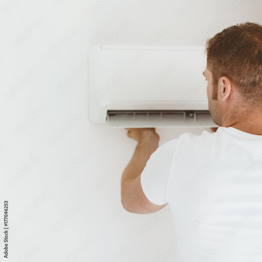 Male technician installing air-conditioning system. Male technician installing air-conditioning system.