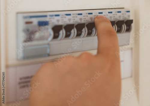 Male hand switching on fuse board. photo