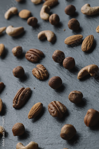 Variety of mixed nuts - almond, hazelnuts and cashew - on the dark slate background with copy space. Top view. Toned