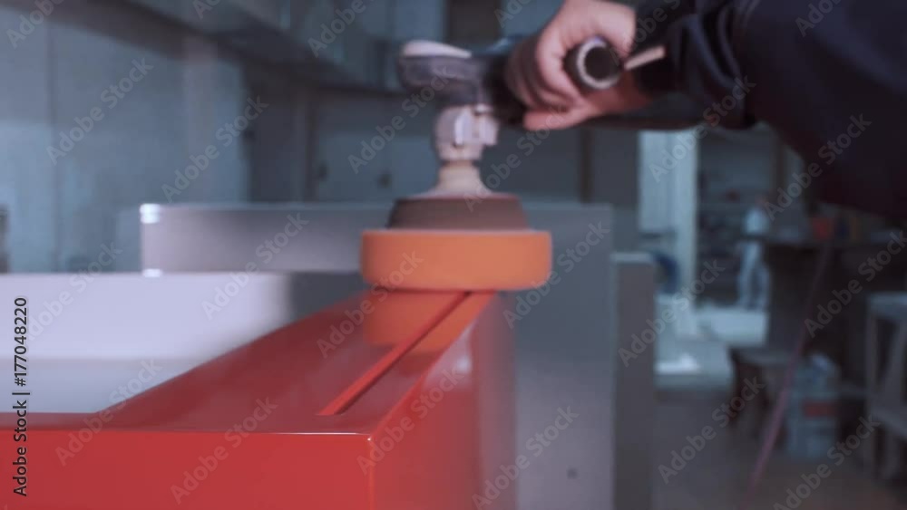 A worker polishes the part after painting A worker polishes the part after painting