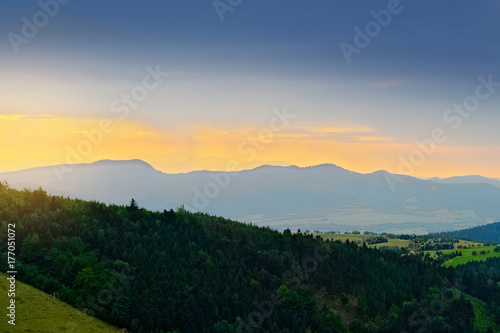 Vast panorama view of foggy valley in the Owl Mountains with silhouette of Sudetes mountain range at dusk. Mountainous countryside landscape in south-west Poland.