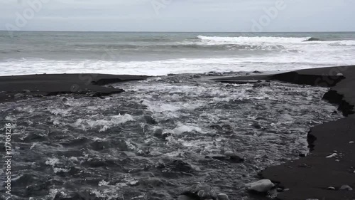 Freshwater stream flowing across rocky beach into ocean. Filmed in slow motion. photo