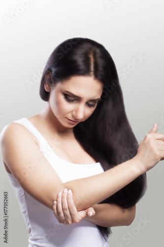 Pain in the elbow. A woman suffering from chronic severe rheumatism. Construction of pain in the elbow and treatment. Painful sensations. The concept of health. On a gray background.