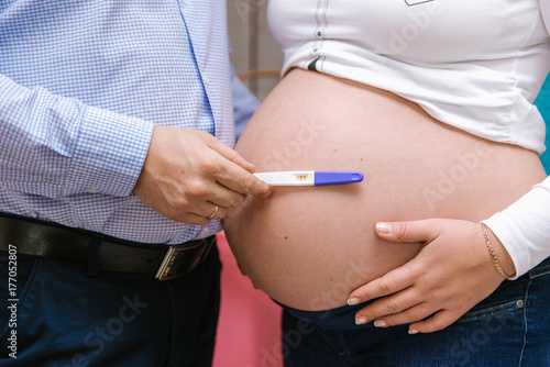 Close up couple expecting a baby - pregnancy test positive, hands on female's tummy