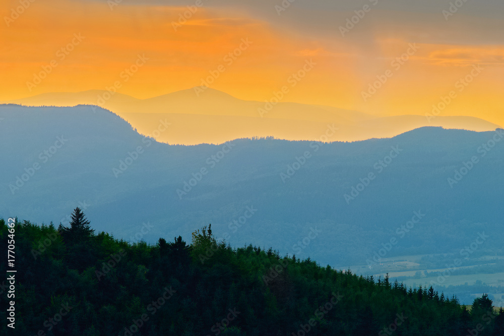 Mountain ridges layered silhouette of Sudetes range with distant Sniezka or Snezka summit at dusk. The Owl Mountains Landscape Park, south-west Poland.