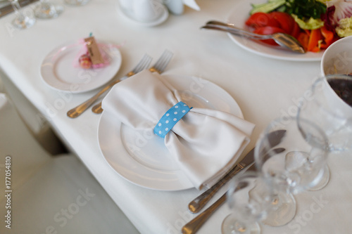 White napkin with ribbon on a white plate. Elegant decoration of table in a restaurant Decorated table for a celebration  wedding or anniversary.