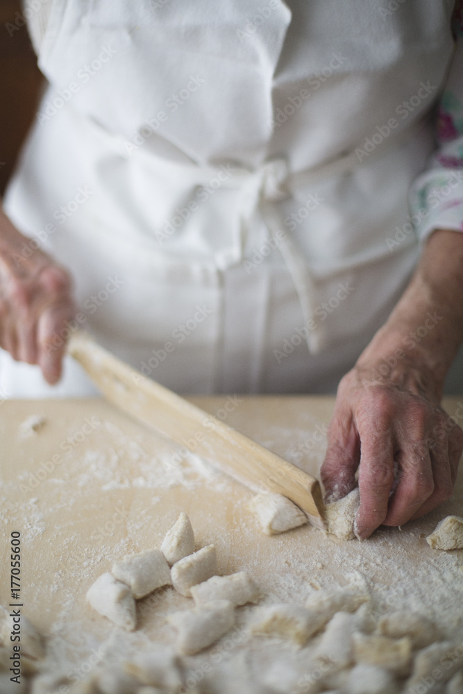 Cutting potato single gnocchi out of stretched dough using dedicated wooden knife Cutting potato single gnocchi out of stretched dough using dedicated wooden knife