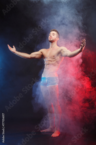 Power, strength, excellent body, bodybuilding, sports concept. Studio shoot of young handsome muscular fit handsome shirtless man with perfect six-pack abs and hands, vertical image © Vadym