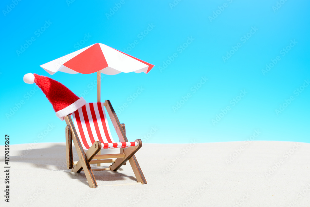 Merry Christmas on beach concept. Lounge chair with umbrella and Santa hat