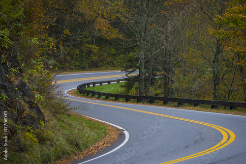 Twisting curvy road winding through fall colorful trees in national park with long exposure car streaks showing motion speed and transportation
