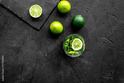 Glass of mojito, lime, mint on black stone background top view copyspace