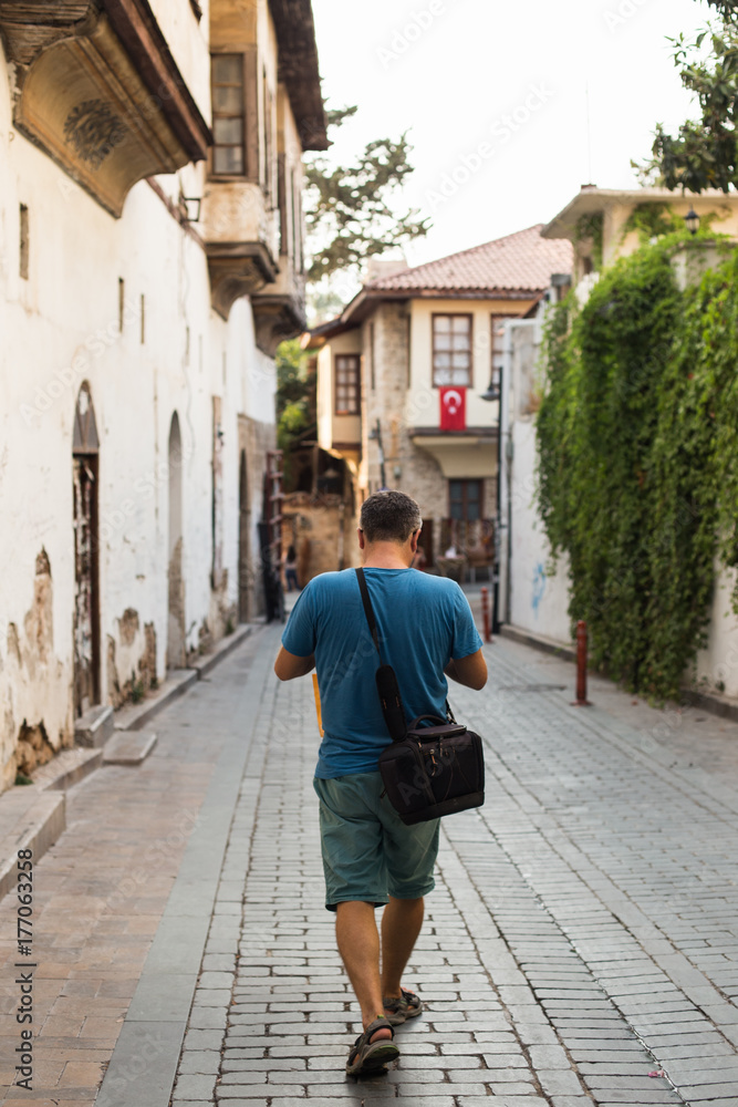 Traveller with camera bag walking through the narrow streets of 