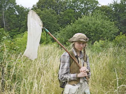 Fotografie A girl entomologist in a field near a forest