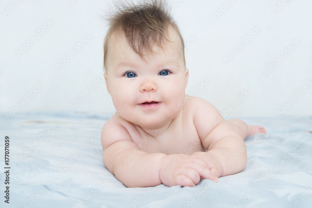 Happy smiling newborn baby portrait cute and adorable in her three month, infant child with blue eyes lying on bed looking at camera Happy smiling newborn baby portrait cute and adorable in her three month, infant child with blue eyes lying on bed looking at camera