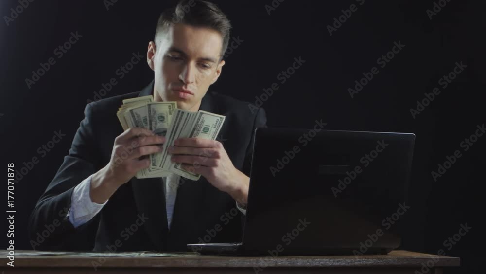 Young businessman counting money sitting at table in office. Concept of salary or profit. Young businessman counting money sitting at table in office. Concept of salary or profit.