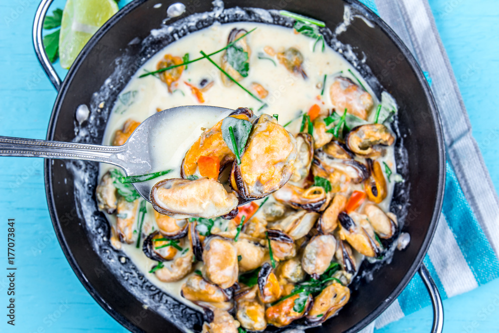 Mussels in creamy milk sauce with aromatic herbs and lemon. Top view Blue background. Top view