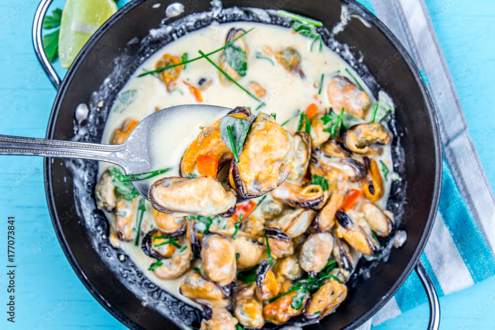 Mussels in creamy milk sauce with aromatic herbs and lemon. Top view Blue background. Top view Mussels in creamy milk sauce with aromatic herbs and lemon. Top view Blue background. Top view