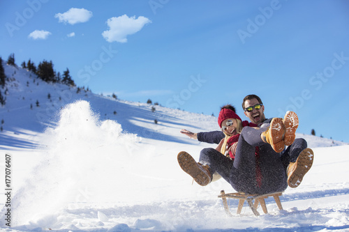 Obraz na plátně Young Couple Sledding And Enjoying On Sunny Winter Day