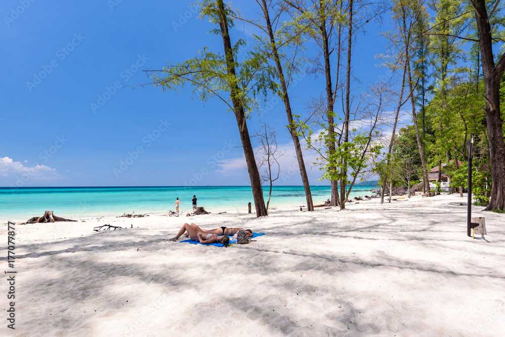 Ladies lie on the sand at beautiful beach of bamboo island near Phi Phi islands in Krabi, Thailand
