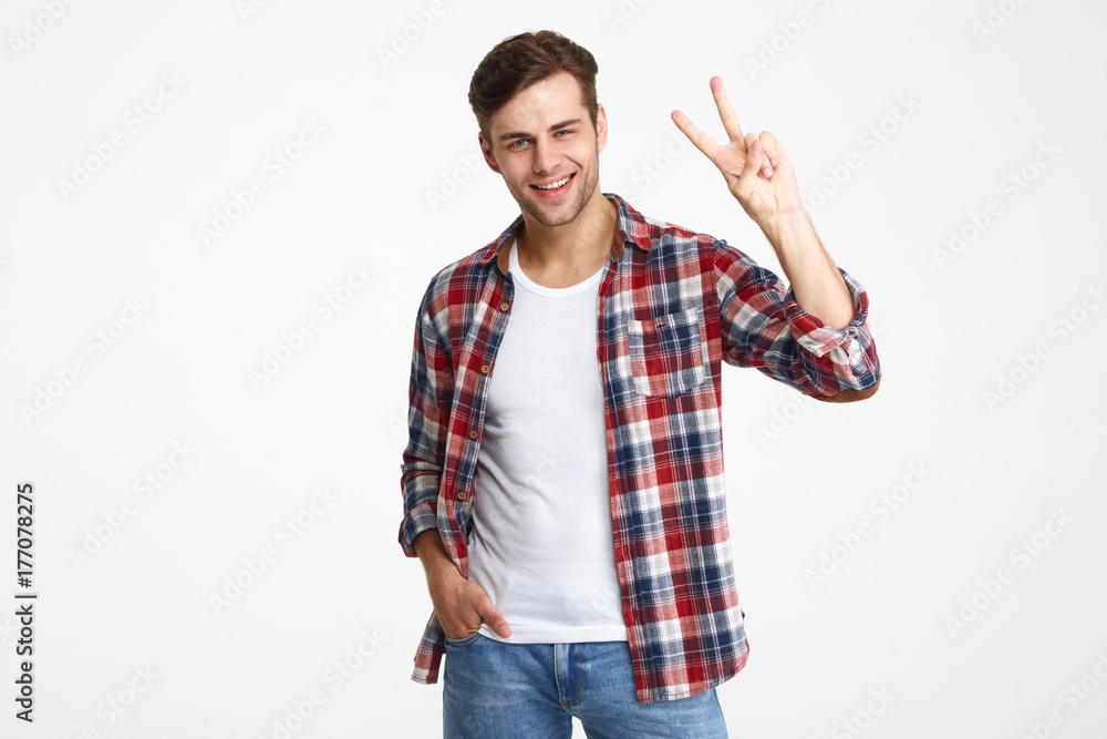Portrait of a cheerful young man showing peace gesture Portrait of a cheerful young man showing peace gesture