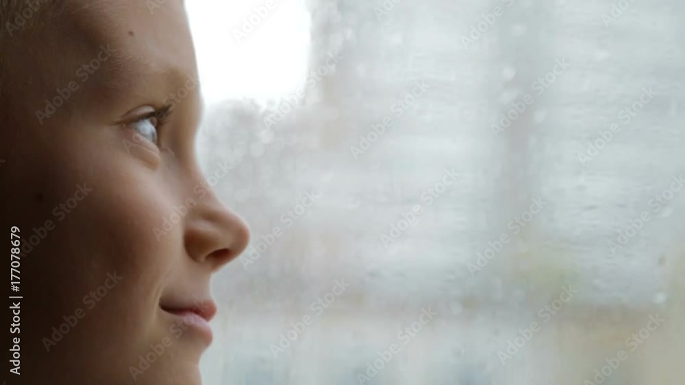 Sad boy looks out the window in rainy weather Sad boy looks out the window in rainy weather