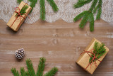 Christmas background gift in Kraft paper tied with twine adorned with spruce branch, lace on  old boards and cedar cones