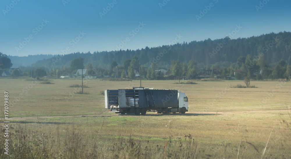 Fototapeta premium Rural landscape with field road and broken truck, blue sky, green forest