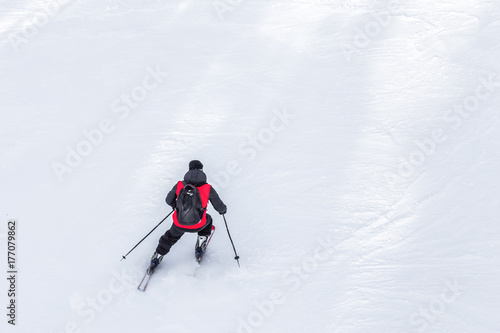 Man skier with red coat and black backpack skiing on fresh white snow on ski slope on Sunny winter day with Copy space in uludag mountain Bursa,Turkey. photo