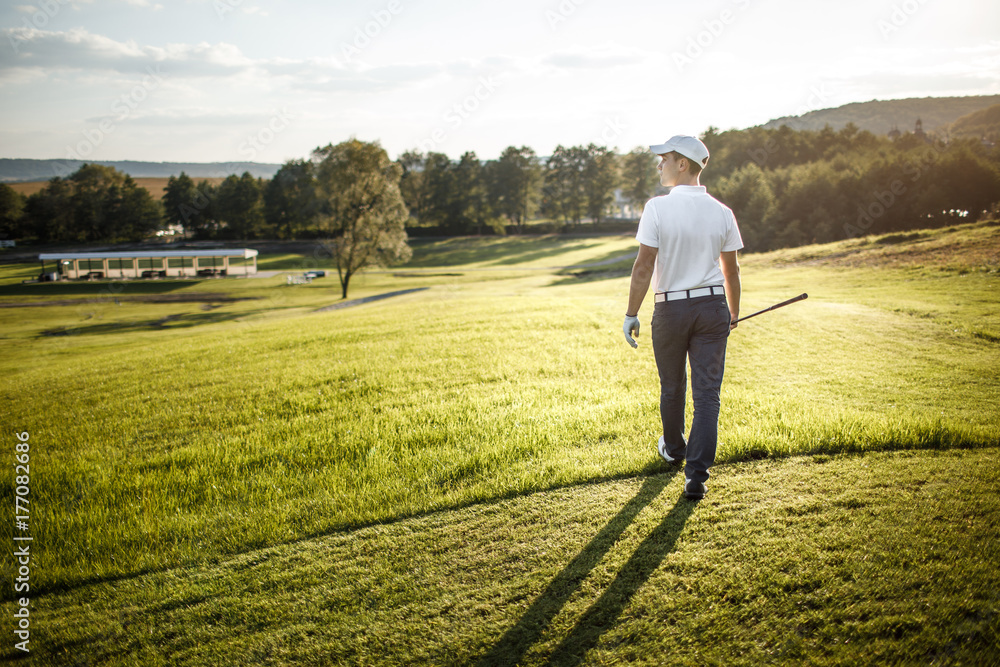 Man playing golf on a golf course in the sun Man playing golf on a golf course in the sun