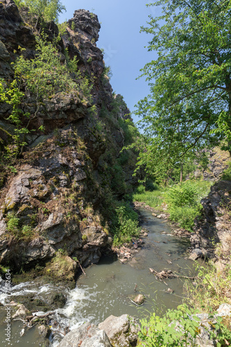 Stream at the bottom of a gorge at the Divoka Sarka on a sunny day. It's a nature reserve on the outskirts of Prague in Czech Republic.