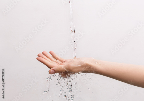 Female hand under the stream of splashing water.