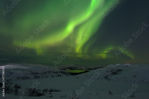 Hills and tundra covered with snow and in the sky the stars, the Aurora. © Moroshka
