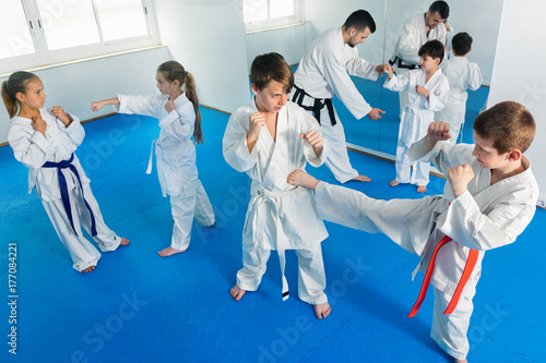 Teenagers practicing new karate moves in pairs in class
