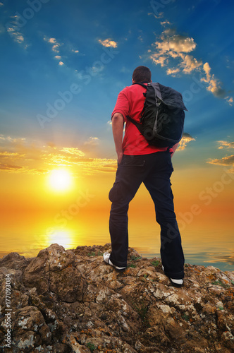 Man Tourist on the mountain edge and sunset sea sky