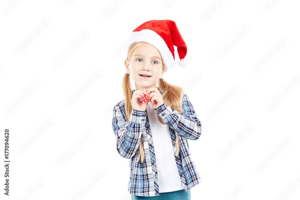 Portrait of sweet little girl in Santa hat blowing into party blower Portrait of sweet little girl in Santa hat blowing into party blower
