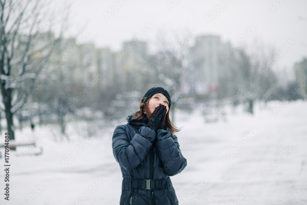 The girl is warming her hands in front of her face. The girl is warming her hands in front of her face.